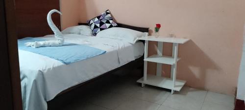 ein Schlafzimmer mit einem Bett und einem Tisch mit einer weißen Tagesdecke in der Unterkunft Hostal La GRAN Familia in Manta