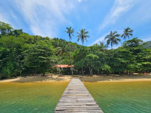 a wooden bridge over a beach with palm trees at Casa Matatiso - casa na Ilha Grande para até 6 pessoas in Angra dos Reis