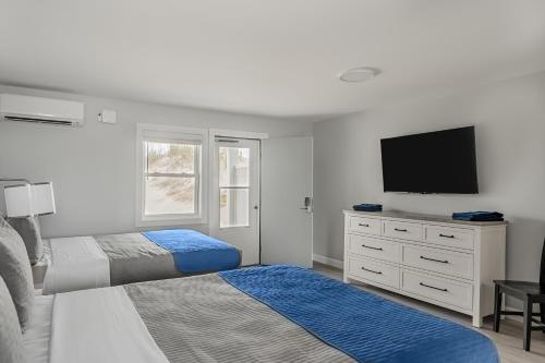 a bedroom with two beds and a flat screen tv at Mia's Boutique Hotel in Nags Head