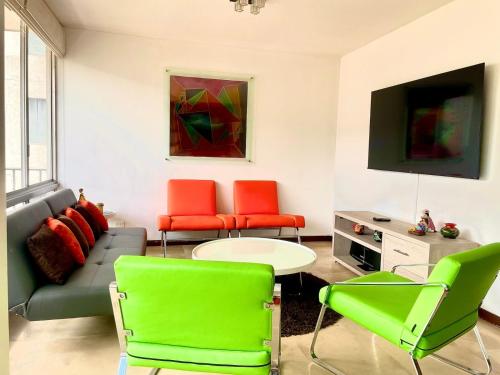 a living room with green and red chairs and a couch at ItsaHome Aparments - Casa del Parque in Quito
