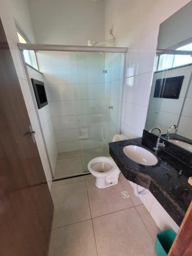 a bathroom with a toilet and a sink and a mirror at Quarto Duplo Comercial - Queen's Hotel in Formosa