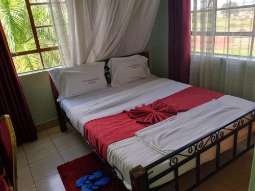 Una cama con un arco rojo en un dormitorio en MUSEUM VIEW HOTEL KISUMU CITY-MILIMANI en Kisumu