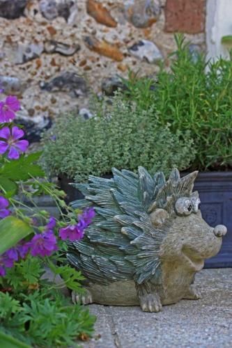a statue of a hedgehog sitting next to flowers at Arden House in Arundel