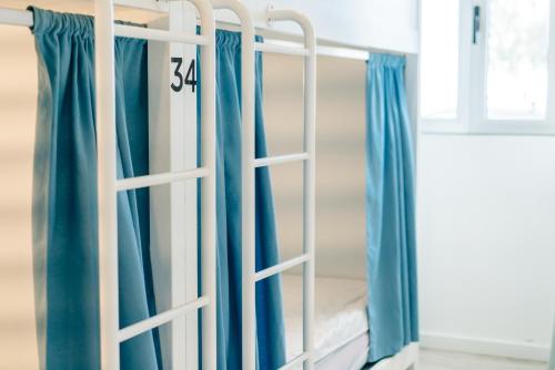 białe łóżeczko dziecięce z niebieskimi zasłonami w pokoju w obiekcie Hostel AzorAzul - Pool & Suite w mieście Ponta Delgada