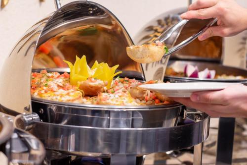 a person is serving food in a large pot of food at Hotel Guadalajara Plaza Expo in Guadalajara