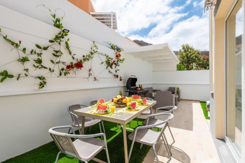 un patio al aire libre con una mesa y sillas con fruta. en Villa Marzella - Luxury Costa Adeje, en Adeje