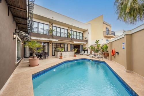 a swimming pool in the backyard of a house at Poolside Paradise Villa Zebbug in Żebbuġ