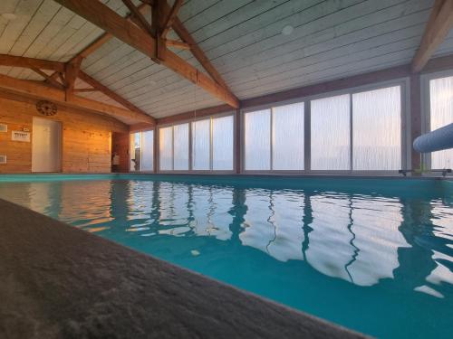 an indoor swimming pool with blue water in a building at Gite Le Cocon de Lily in Saint-Savin-de-Blay