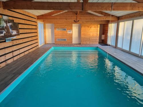 a swimming pool in a wooden house with blue water at Gite Le Cocon de Lily in Saint-Savin-de-Blay