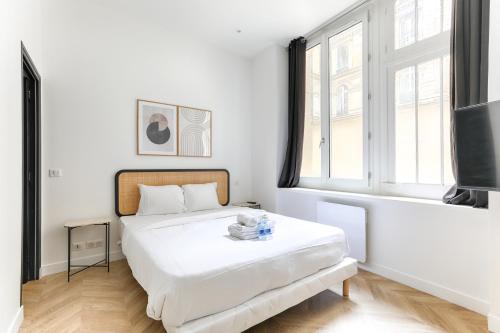 une chambre blanche avec un lit et une grande fenêtre dans l'établissement Mogador - Opéra Haussmann Charming Apartment 4P 1BDR, à Paris