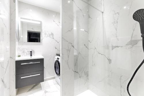 une salle de bain blanche avec une douche et un lavabo dans l'établissement Mogador - Opéra Haussmann Charming Apartment 4P 1BDR, à Paris