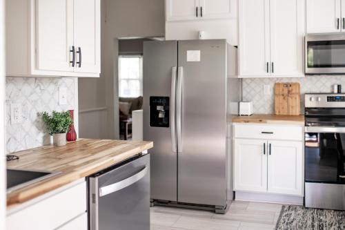 La cuisine est équipée de placards blancs et d'un réfrigérateur en acier inoxydable. dans l'établissement Bluewater Downtown Cottage, à Wilmington
