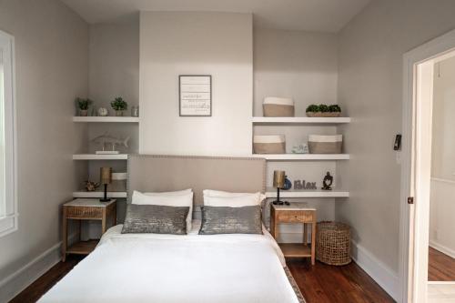1 dormitorio con 1 cama con paredes y estanterías blancas en Bluewater Downtown Cottage, en Wilmington