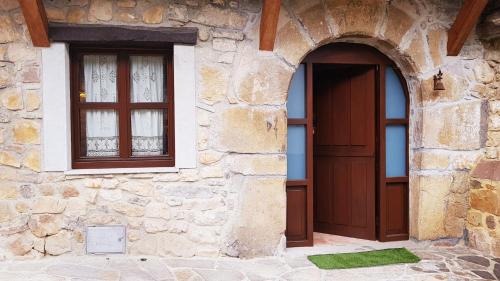 un edificio de piedra con puerta y 2 ventanas en Vivienda Vacacional El Ventanuco, en Buelna