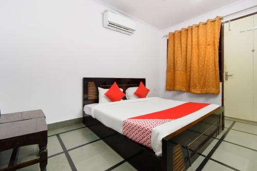 een slaapkamer met een bed met rode kussens bij Flagship Sitar Guest House in Rudrapur