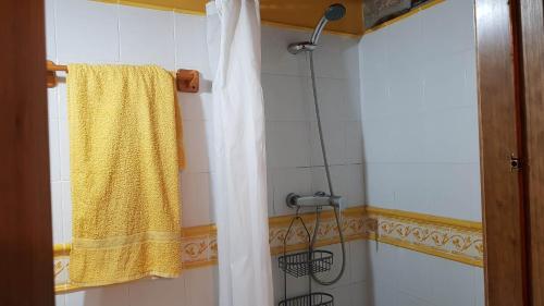 y baño con ducha y toalla amarilla. en Vivienda Vacacional El Ventanuco, en Buelna