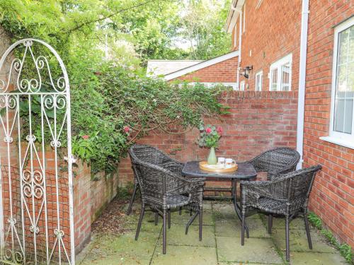 a patio with a table and chairs and a brick wall at Sea View Cottage in Menai Bridge