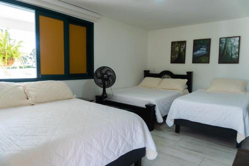 a bedroom with two beds and a window at Colina del Sol Hotel Hacienda in Quimbaya