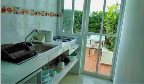 cocina con fregadero, fogones y ventana en Departamentos Villas Capdeviel, en Cancún