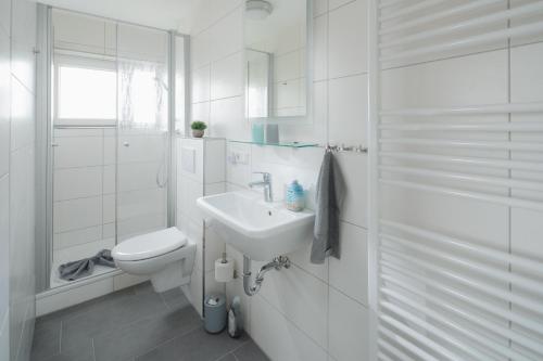 a white bathroom with a sink and a toilet at Haus Enna Enna 2 in Norderney