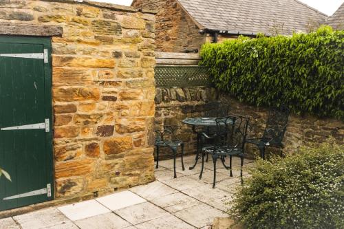 a patio with a table and chairs next to a stone wall at The Peacock at Barlow in Chesterfield