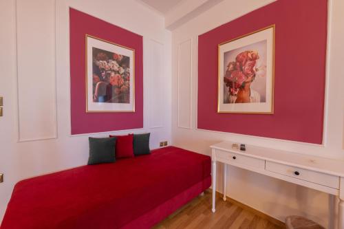 a room with a red couch and two paintings at L Suites The Writer's House in Gythio
