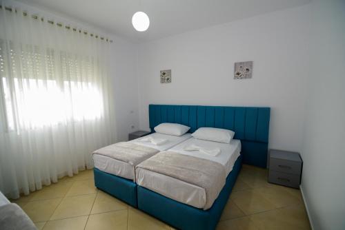 a bedroom with a blue bed and a window at Harris&Arvien Apartment's in Vlorë