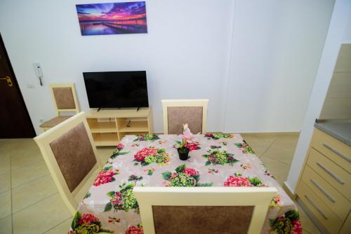 a dining room with a table with flowers on it at Harris&Arvien Apartment's in Vlorë