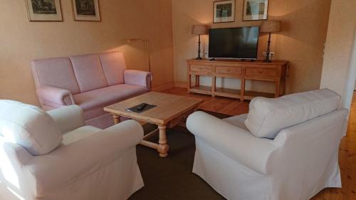 a living room with two chairs and a tv at Rentei 8 in Lüdersburg
