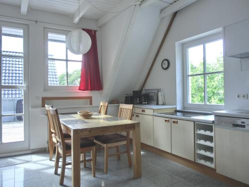 een keuken met een tafel, stoelen en ramen bij Ferienwohnung MH2 "Sunrise" in Rostock