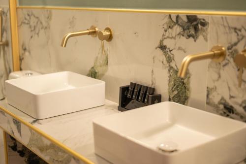 a bathroom with two white sinks on a counter at L Suites The Writer's House in Gythio