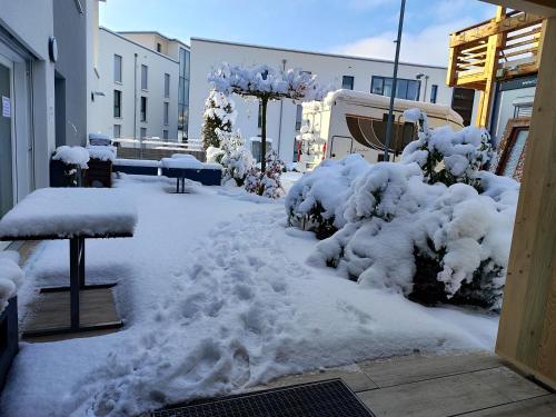 a snow covered yard with benches and benches at Hotel Gästehaus Stock Zimmer Teekännle in Friedrichshafen