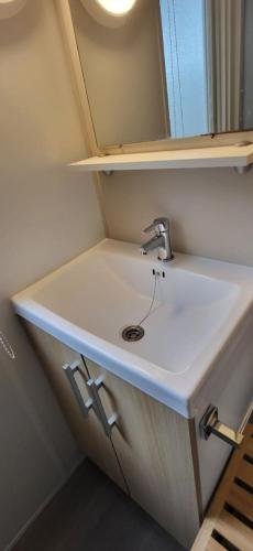 une salle de bain avec un lavabo et un miroir dans l'établissement MOBILHOME Lodge 3 chambres, 500m plage, camp 5 étoiles, à Vendres