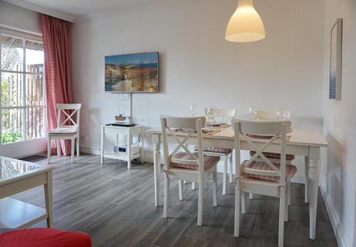 a white dining room with a table and chairs at Keitum in Keitum