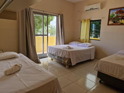 a hotel room with two beds and a window at HOTEL E RESTAURANTE ILHA BELA in Soure