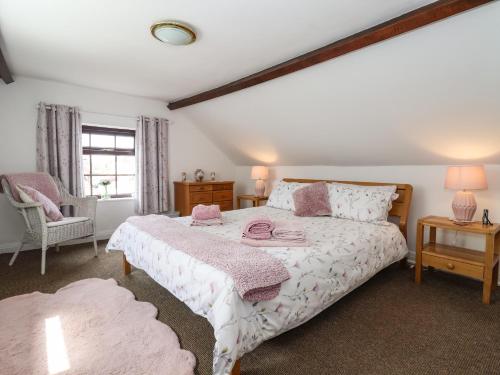 a bedroom with a bed and a chair and a window at Rhodale Cottage in Barmston