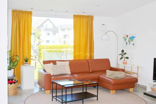 a living room with a brown couch and yellow curtains at Ferienhaus Kitzenwiese in Friedrichshafen
