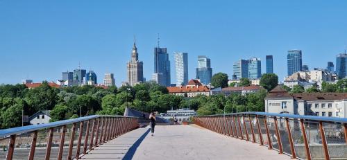 Best Warsaw Panorama Bridge by Better Place في وارسو: امرأة تقف على جسر مع مدينة في الخلفية