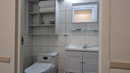 a white bathroom with a toilet and a sink at 182 Heguangju in Hung-i-li