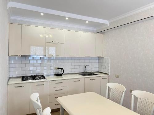 a kitchen with white cabinets and a table and chairs at Mount Inn Villa in Bakuriani