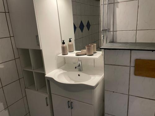 W białej łazience znajduje się umywalka i lustro. w obiekcie Vollmers w Malmö