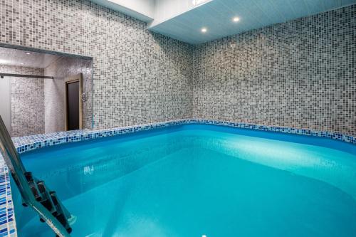 a large swimming pool in a bathroom with blue water at Golden Tulip Rosa Khutor Hotel in Estosadok