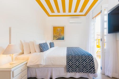 a white bedroom with a bed and a coffered ceiling at Villa Raphael in Búzios