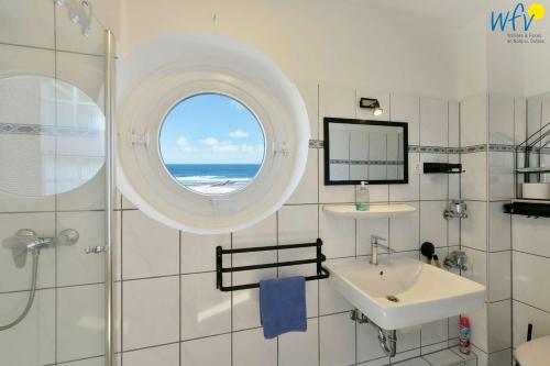a bathroom with a sink and a mirror and a window at Haus Poseidon Ferienwohnung Nordseeblick in Wangerooge