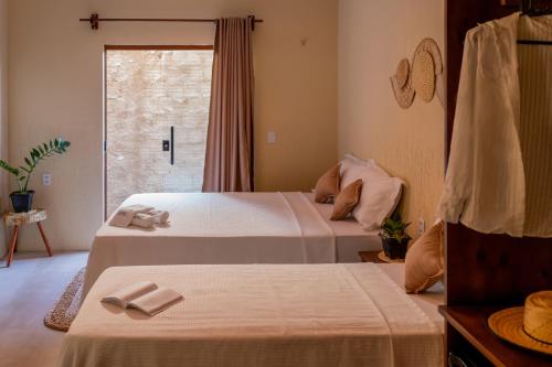 a bedroom with two beds and a window at Pousada Rota do Kite Preá in Prea