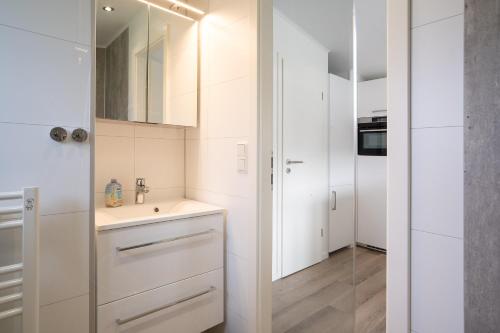 a white kitchen with a sink and a mirror at Ostseecamp Chalet Haffkrug No 55 in Scharbeutz