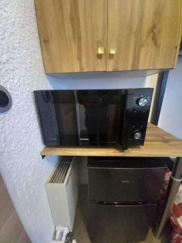 a microwave sitting on a wooden shelf in a kitchen at Studio plein centre des 2 Alpes in Les Deux Alpes