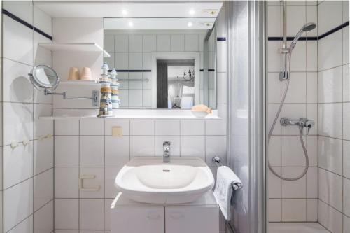 een witte badkamer met een wastafel en een douche bij Strandkorb in der Villa Medici in Norderney