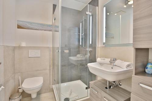 La salle de bains est pourvue de toilettes, d'un lavabo et d'une douche. dans l'établissement Seesternresidenz Appartement 21, à Scharbeutz