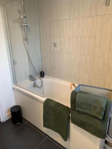 La salle de bains est pourvue d'une baignoire et de 2 serviettes vertes. dans l'établissement « stef one « centre ville 2 chambres 3 voyageurs, à Valenciennes